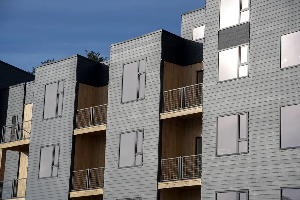 A close-up of the side of Seavey Terraces's grey siding, black-trim windows, and wood decks